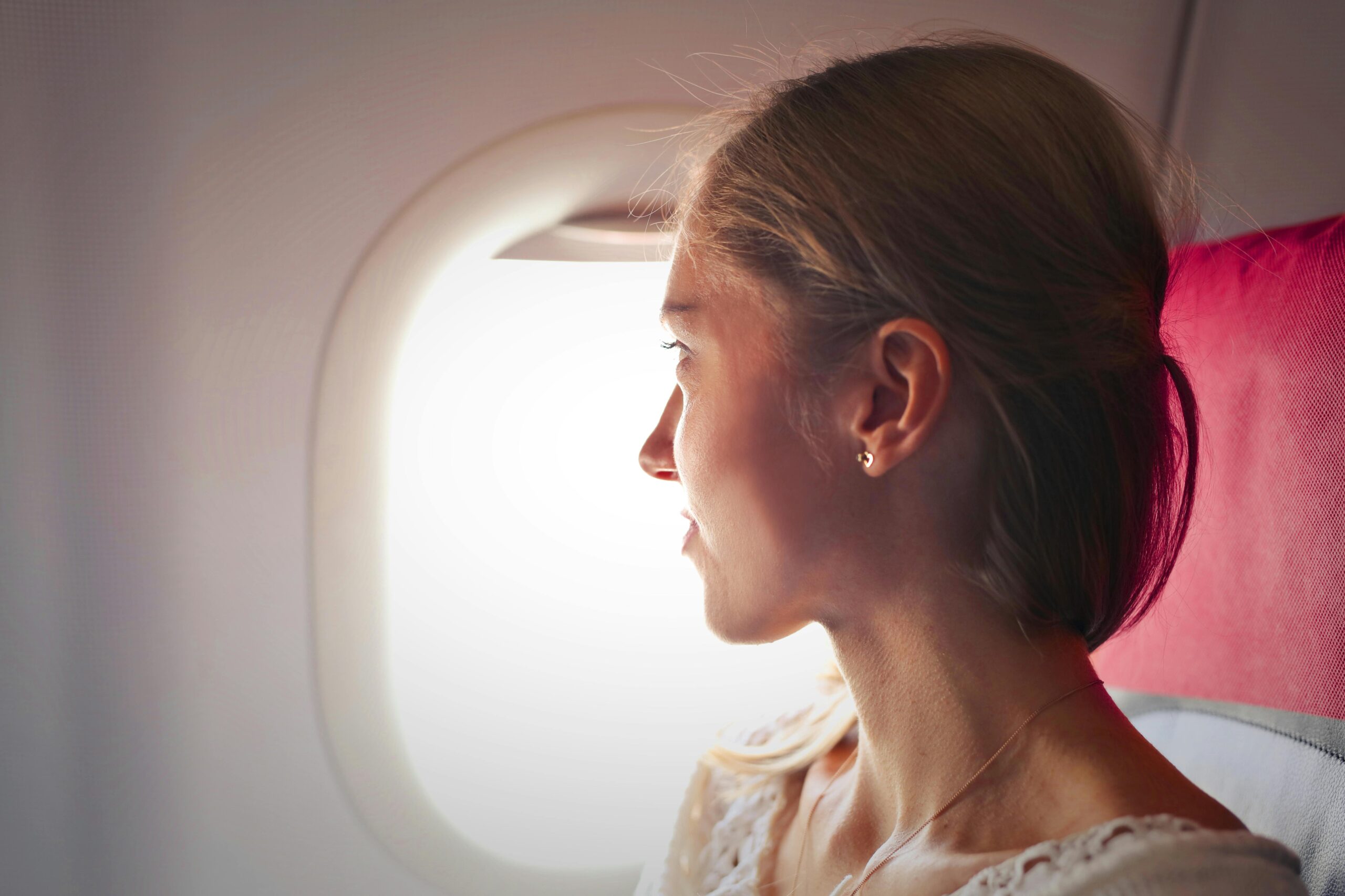 A woman on an airplane, looking out the window.